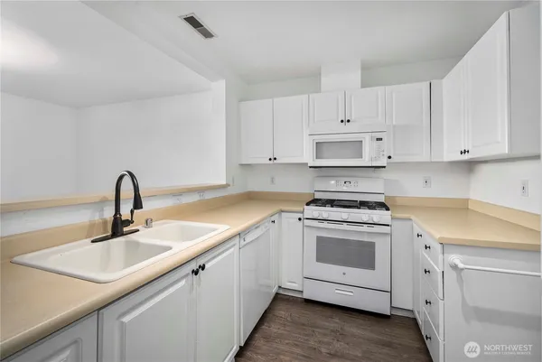 a kitchen with white cabinets and appliances