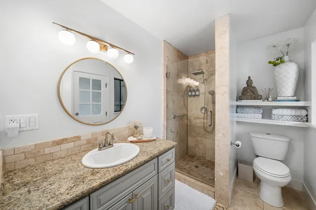 a bathroom with a granite countertop toilet a sink and a mirror