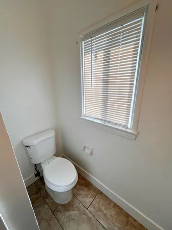 a white toilet sitting in a bathroom next to a window
