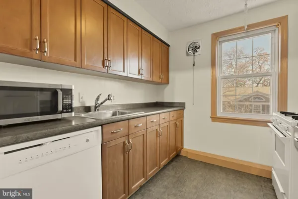 a kitchen with granite countertop white cabinets stainless steel appliances a sink and wooden floor