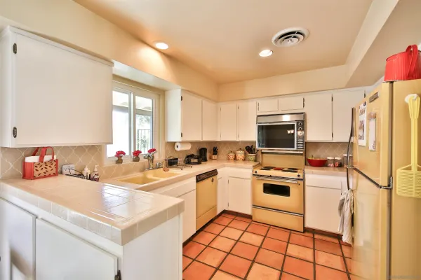 a kitchen with a sink a stove a refrigerator and white cabinets