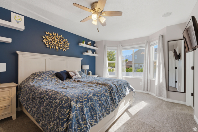11189 Ohenry Road East Sandy, UT 84070 - Photo 14 of 44 Carpeted bedroom featuring a bay window, ceiling fan with integrated lighting, and a wall-mounted television