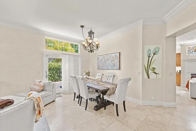 a view of a dining room with furniture a chandelier and a window