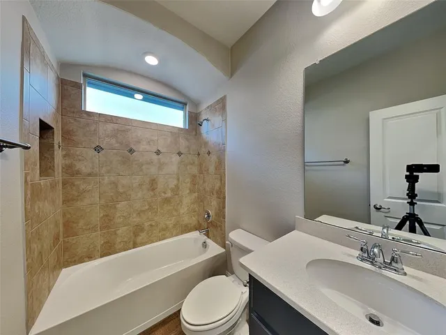 a bathroom with a bathtub shower sink vanity mirror and toilet