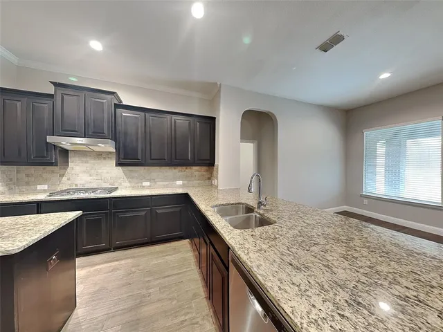 a kitchen with granite countertop sink stove and cabinets