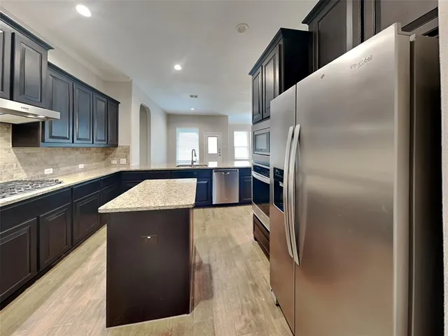 a kitchen with stainless steel appliances granite countertop a refrigerator a sink and a stove