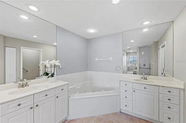 a en suite bathroom with a double vanity sink a mirror and a bathtub