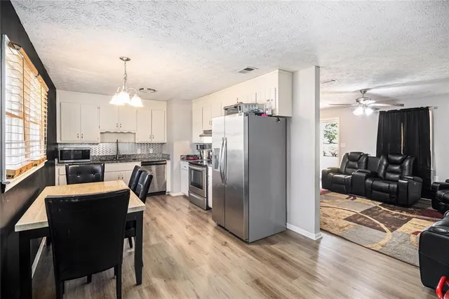 a kitchen with stainless steel appliances a refrigerator a stove a sink a dining table and chairs