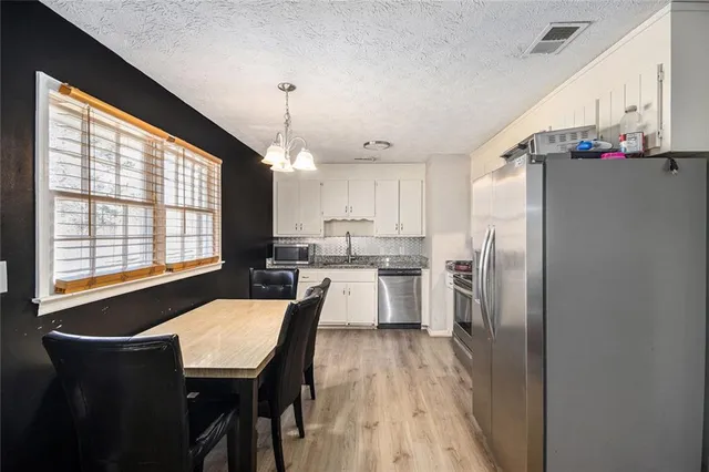 a kitchen with a table chairs refrigerator and window