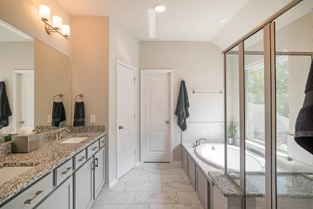 a bathroom with a granite countertop sink a mirror and a shower