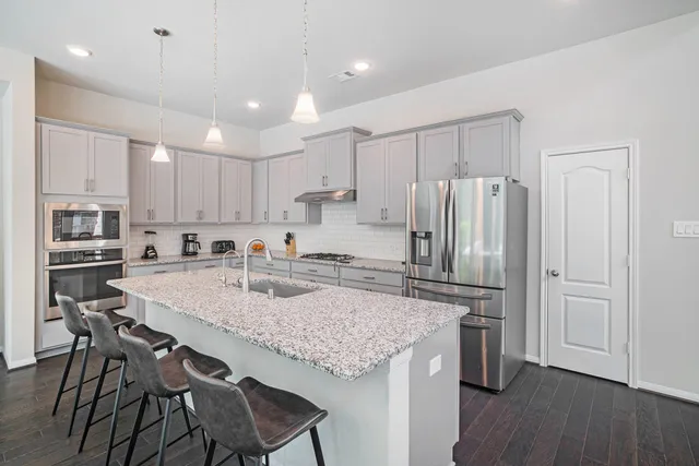 a kitchen with stainless steel appliances granite countertop a table chairs sink refrigerator and microwave