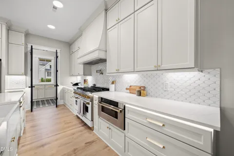 a large white kitchen with lots of counter space a sink and appliances