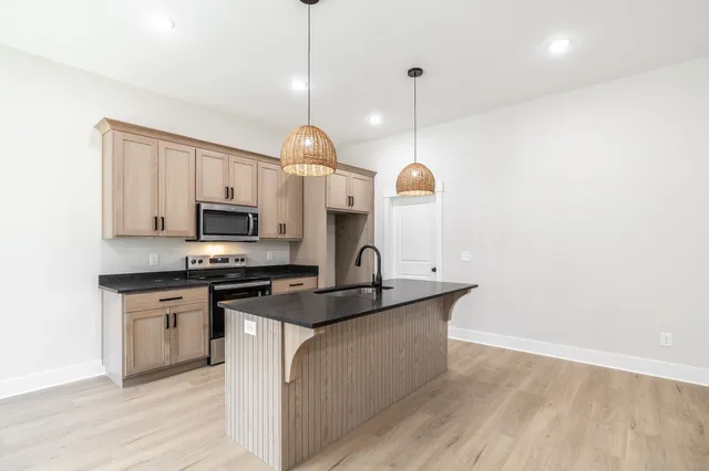 a kitchen with stainless steel appliances granite countertop a sink a stove and a wooden floors