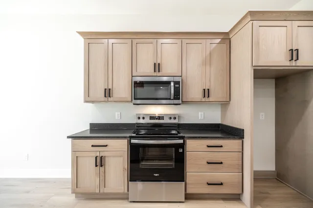 a kitchen with granite countertop a stove and a microwave