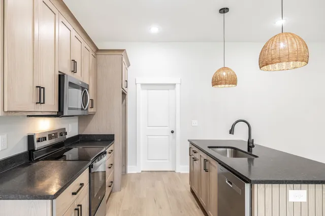 a kitchen with stainless steel appliances granite countertop a sink a stove and a refrigerator