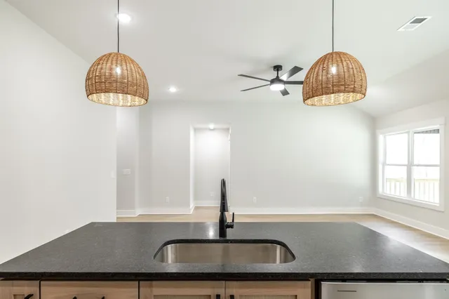 a kitchen with stainless steel appliances granite countertop a sink a window and wooden floor
