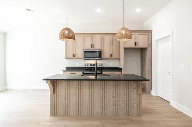 a kitchen with stainless steel appliances granite countertop a sink a refrigerator and a stove