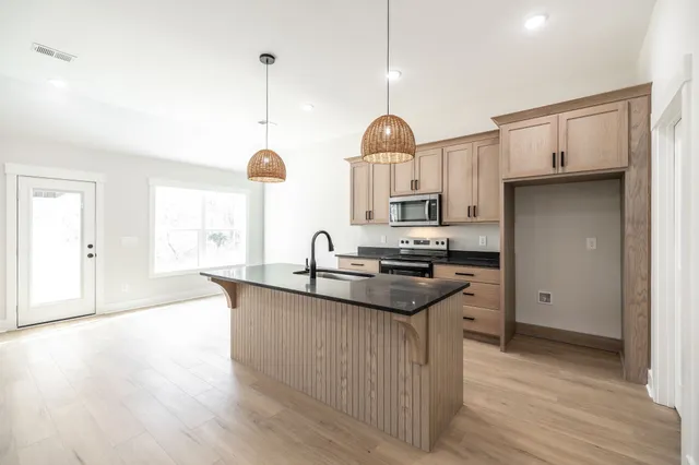 a kitchen with stainless steel appliances granite countertop a sink a stove and a wooden floors