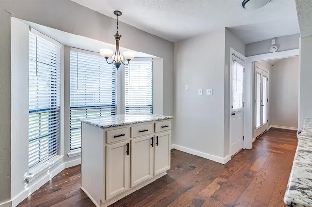 a kitchen with kitchen island granite countertop a stove a sink and wooden floors