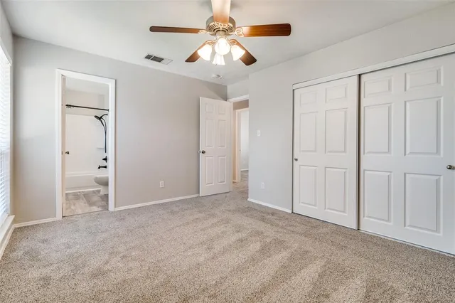 an empty room with closet and a ceiling fan