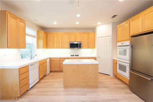 a view of a kitchen with kitchen island wooden floor center island and stainless steel appliances