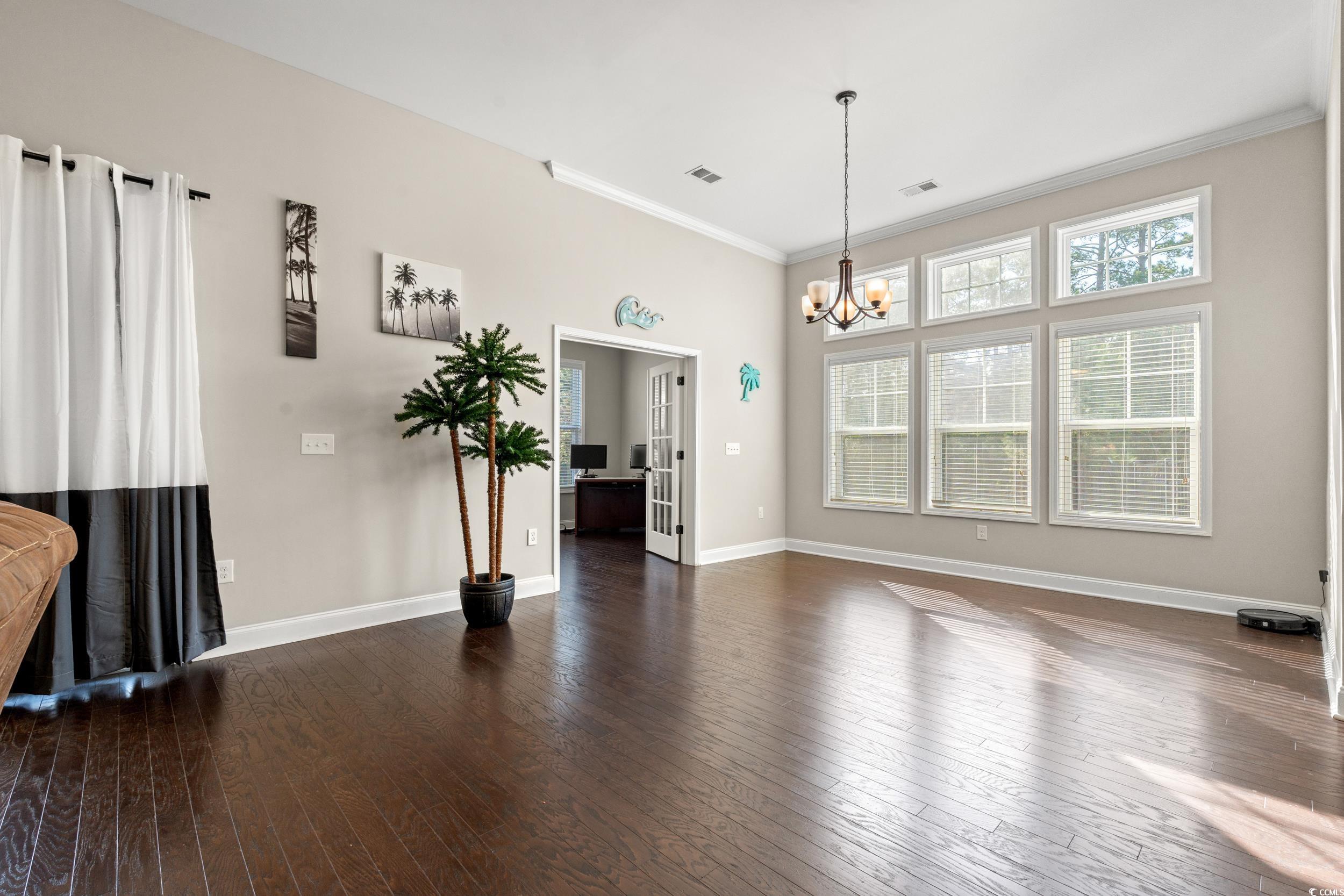 126 Viareggio Road Myrtle Beach, SC 29579 - Photo 12 of 40 Unfurnished living room with dark wood-style floors, a chandelier, and ornamental molding