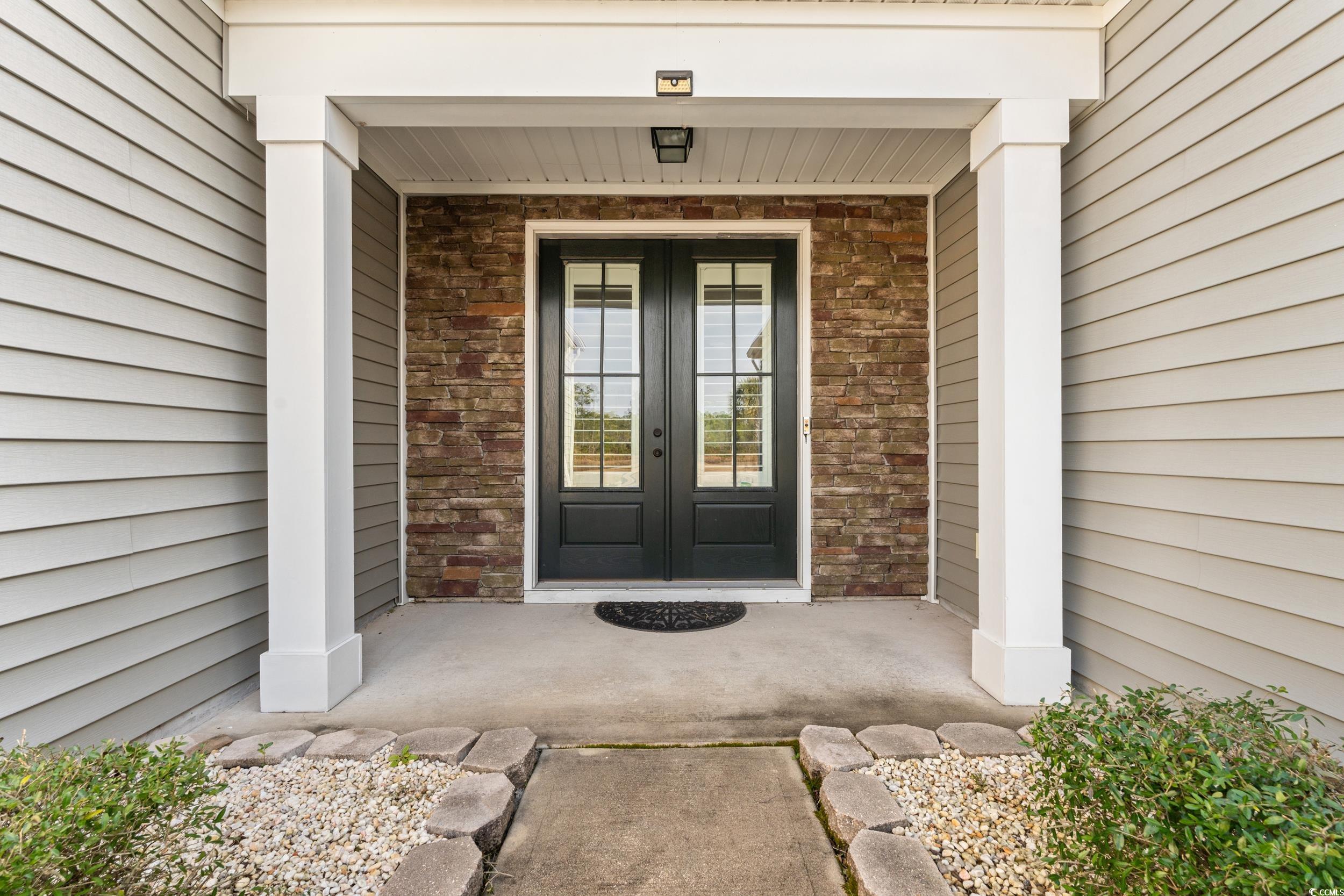 126 Viareggio Road Myrtle Beach, SC 29579 - Photo 2 of 40 View of exterior entry featuring a porch, brick siding, stone siding, and french doors