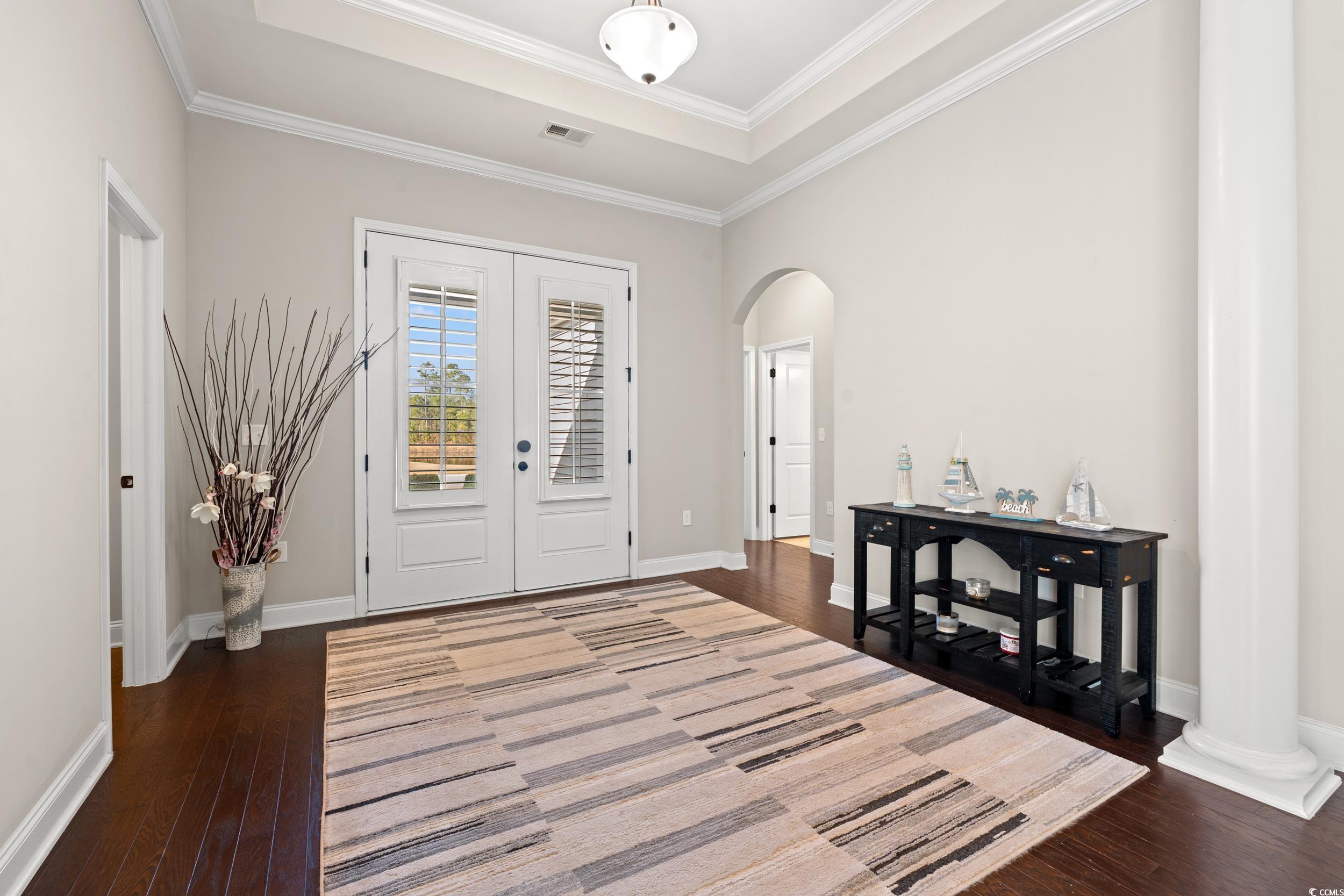 126 Viareggio Road Myrtle Beach, SC 29579 - Photo 3 of 40 Foyer entrance featuring ornamental molding, a tray ceiling, french doors, arched walkways, and dark wood-style floors