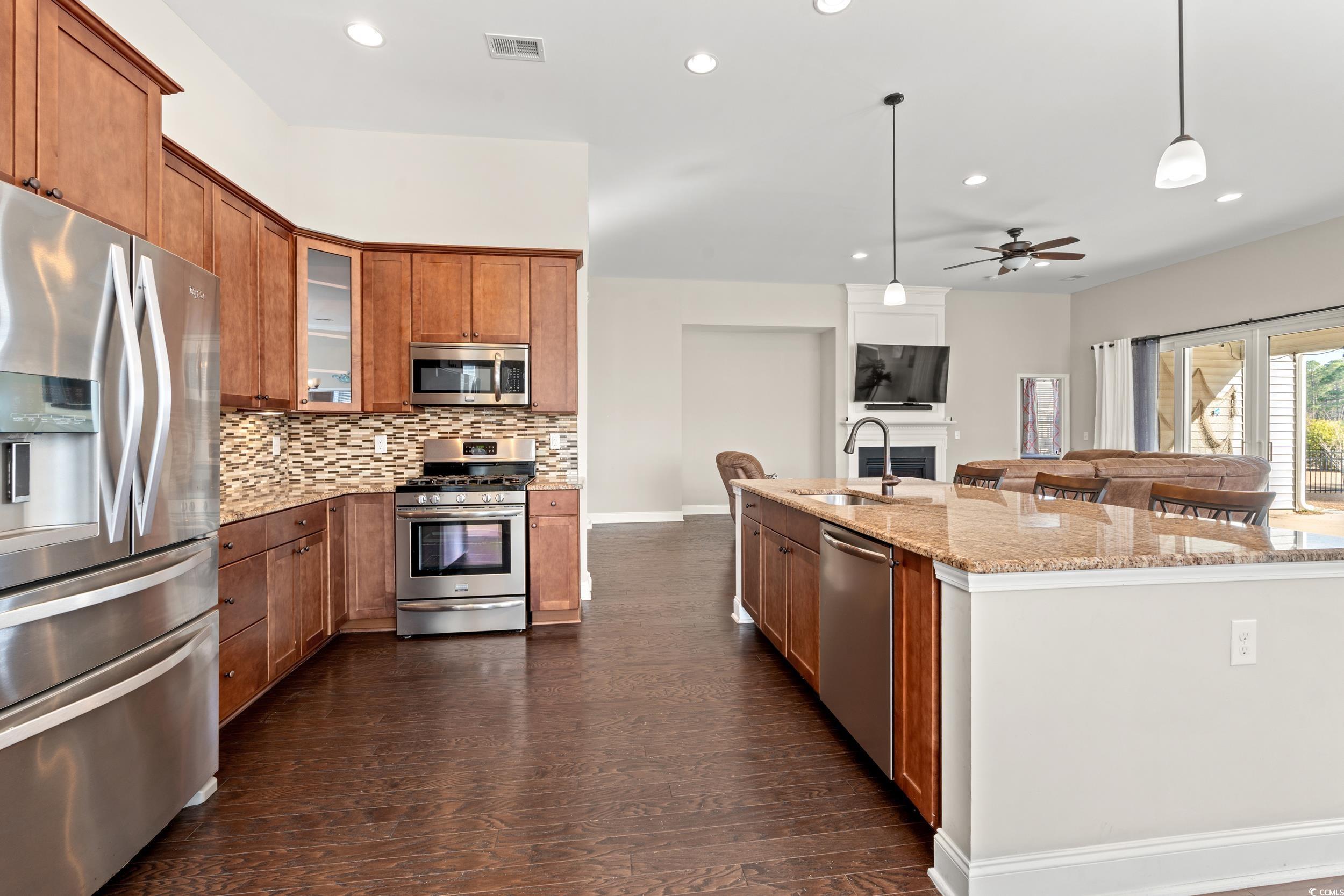 126 Viareggio Road Myrtle Beach, SC 29579 - Photo 4 of 40 Kitchen featuring pendant lighting, appliances with stainless steel finishes, brown cabinets, light stone counters, and recessed lighting