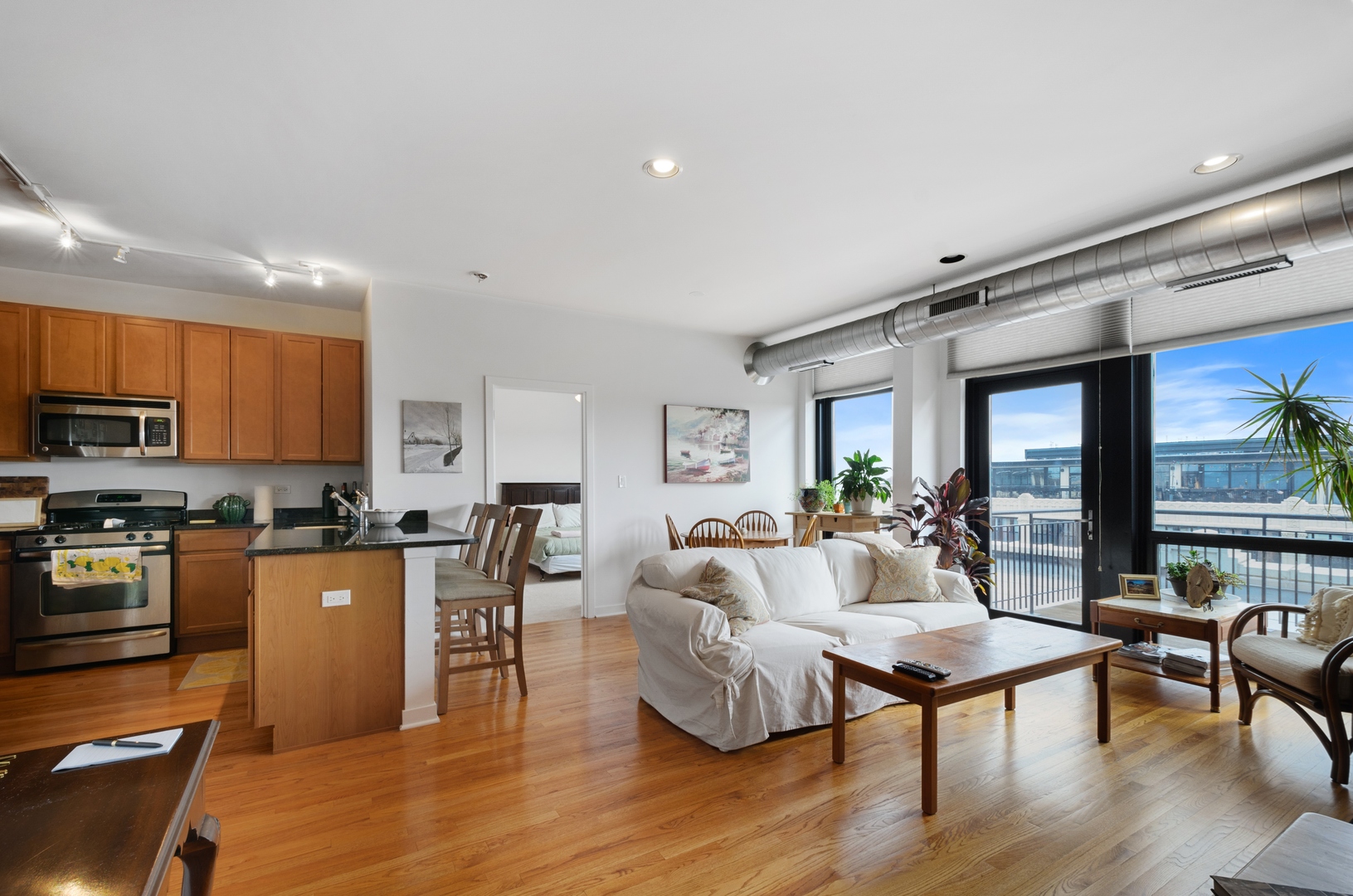 1110 West 15th Street, Unit 412 Chicago, IL 60608 - Photo 6 of 19 a living room with stainless steel appliances a dining table wooden floor furniture and a kitchen view