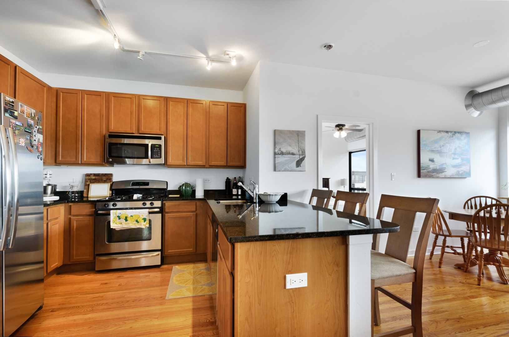 1110 West 15th Street, Unit 412 Chicago, IL 60608 - Photo 7 of 19 a kitchen with stainless steel appliances granite countertop a stove top oven a sink dishwasher a dining table and chairs with wooden floor