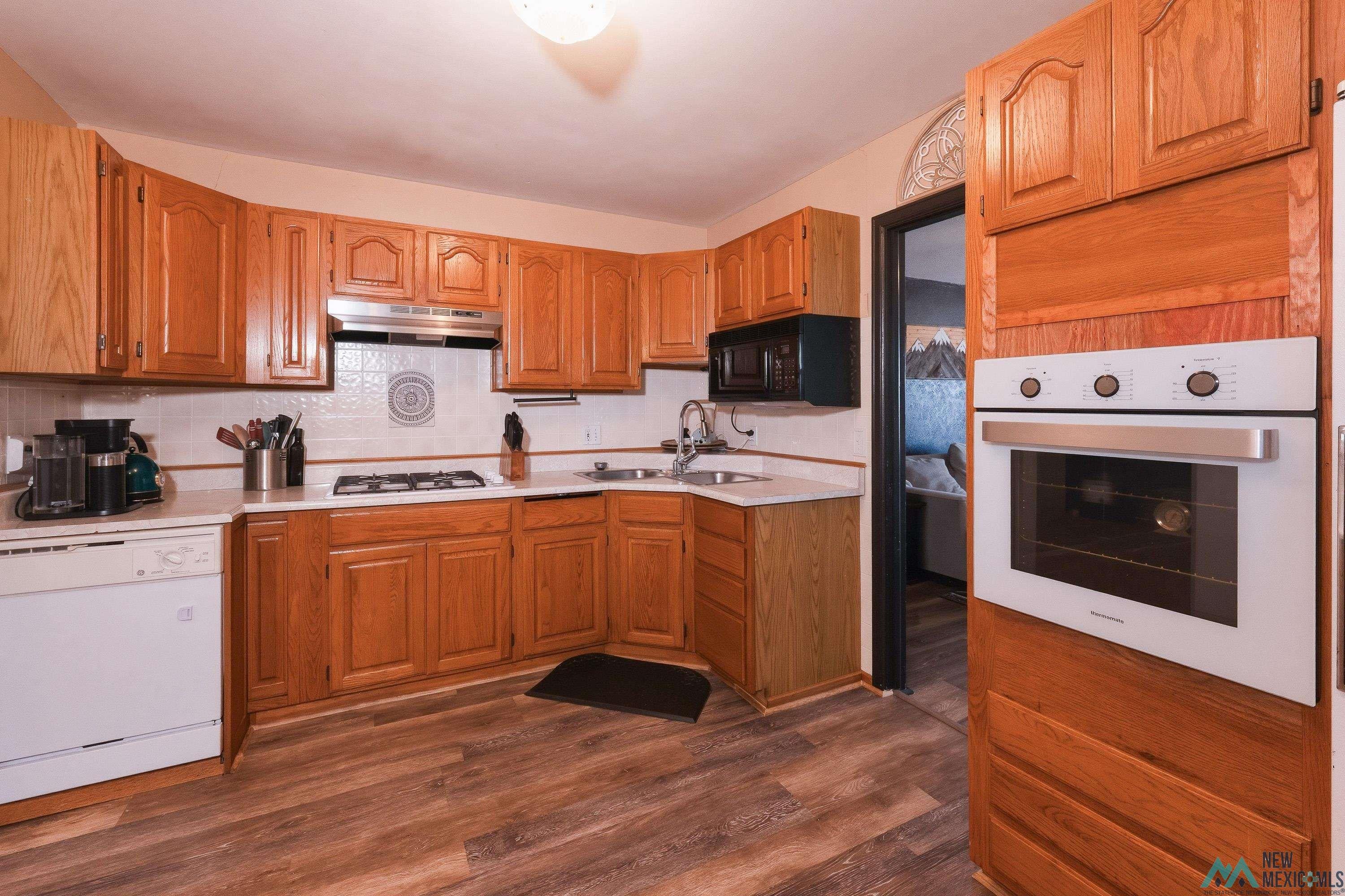 1432 South 5th Street Raton, NM 87740 - Photo 9 of 32 Kitchen with light countertops, white appliances, dark wood-style flooring, and wood finish cabinetry
