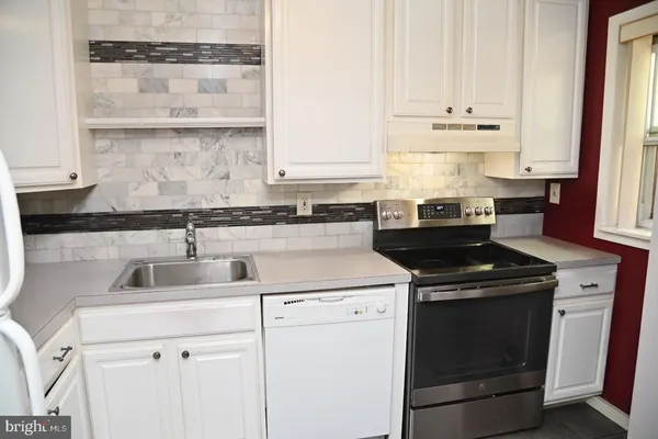 a kitchen with cabinets appliances a sink and a window