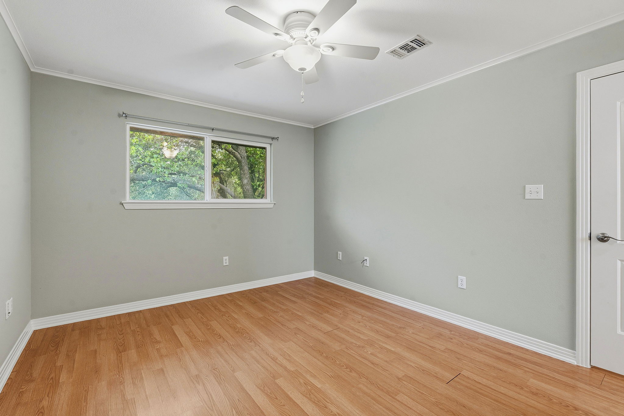 1422 Collier Street, Unit 203 Austin, TX 78704 - Photo 13 of 21 This room features light wood flooring, a window offering views of greenery, and a ceiling fan