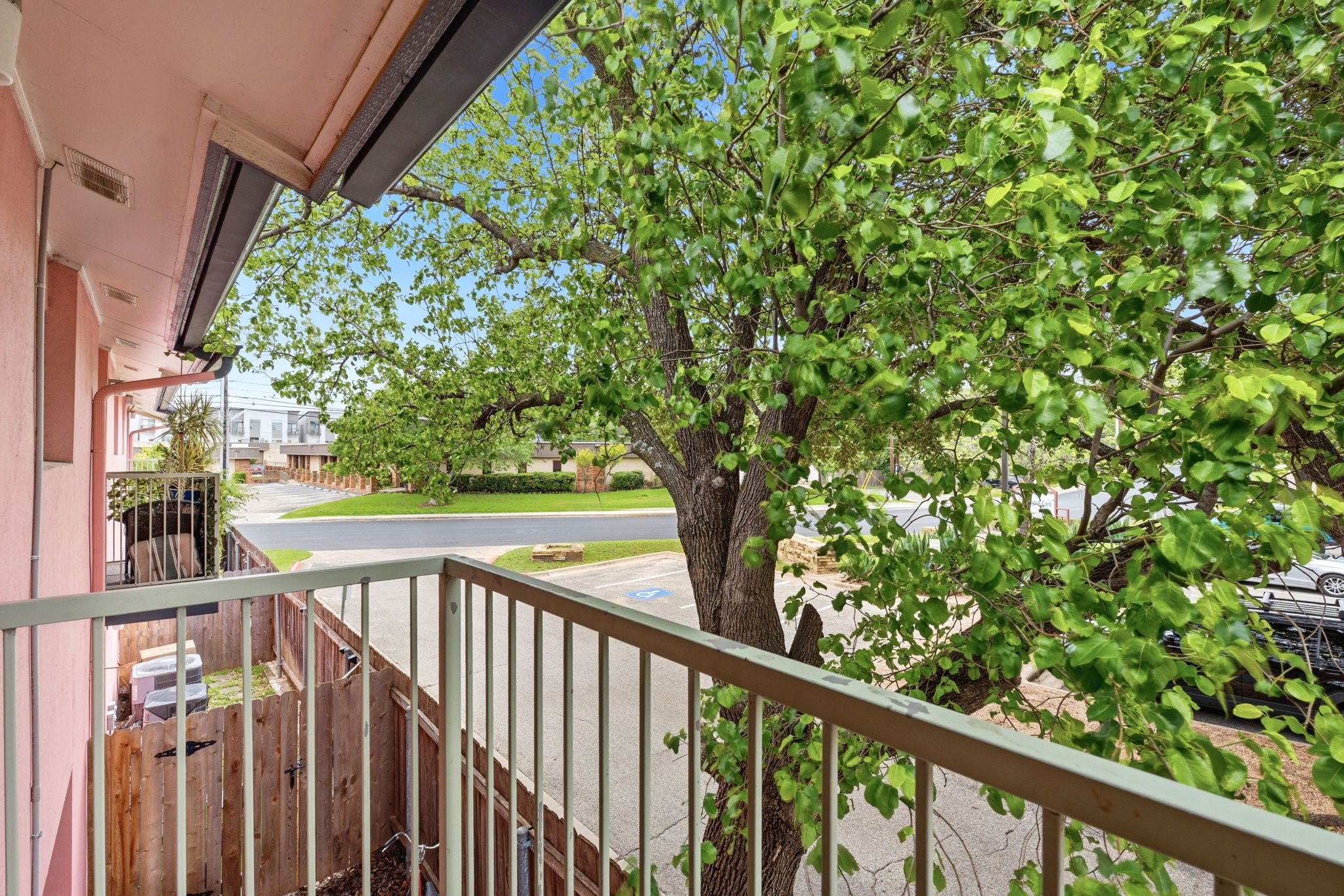 1422 Collier Street, Unit 203 Austin, TX 78704 - Photo 19 of 21 This property features a balcony with a metal railing and a view of a mature tree with vibrant green foliage