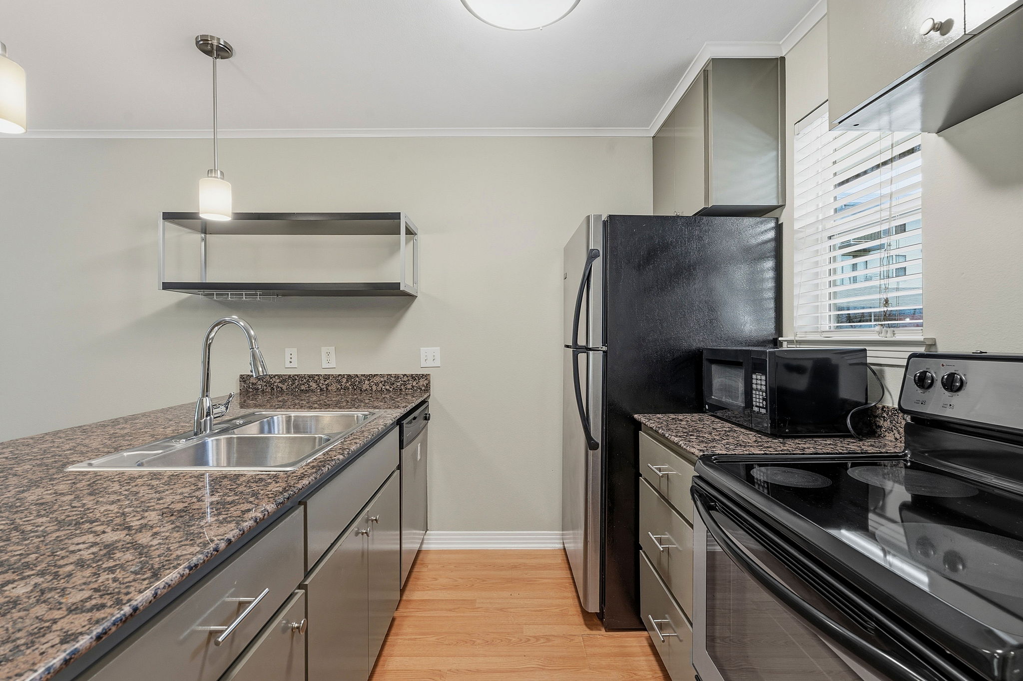 1422 Collier Street, Unit 203 Austin, TX 78704 - Photo 5 of 21 The kitchen features granite countertops, stainless steel appliances, a double basin sink, and wood flooring