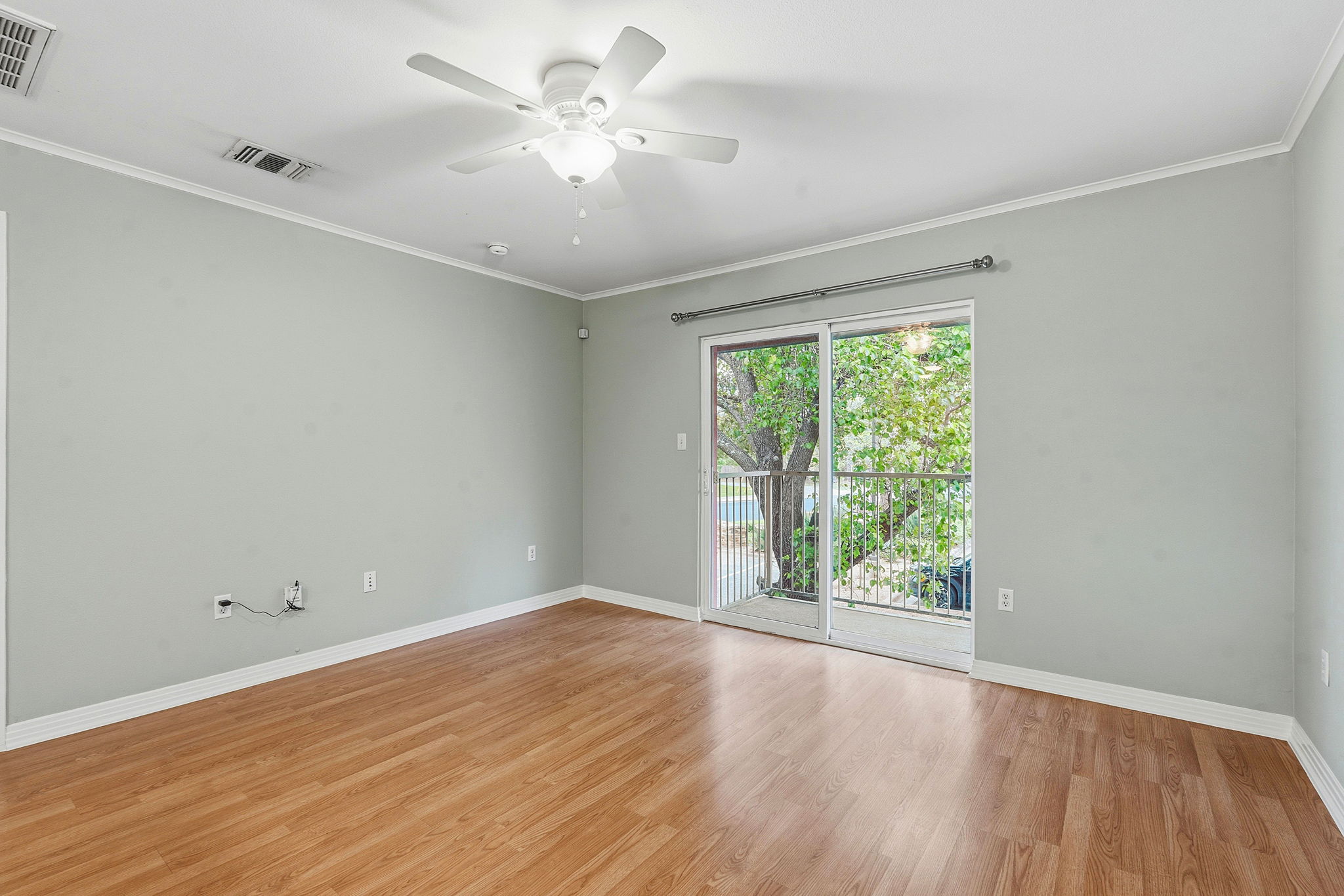 1422 Collier Street, Unit 203 Austin, TX 78704 - Photo 10 of 21 Living area featuring wood flooring, a ceiling fan, and sliding glass doors that open to an outdoor space with a metal railing