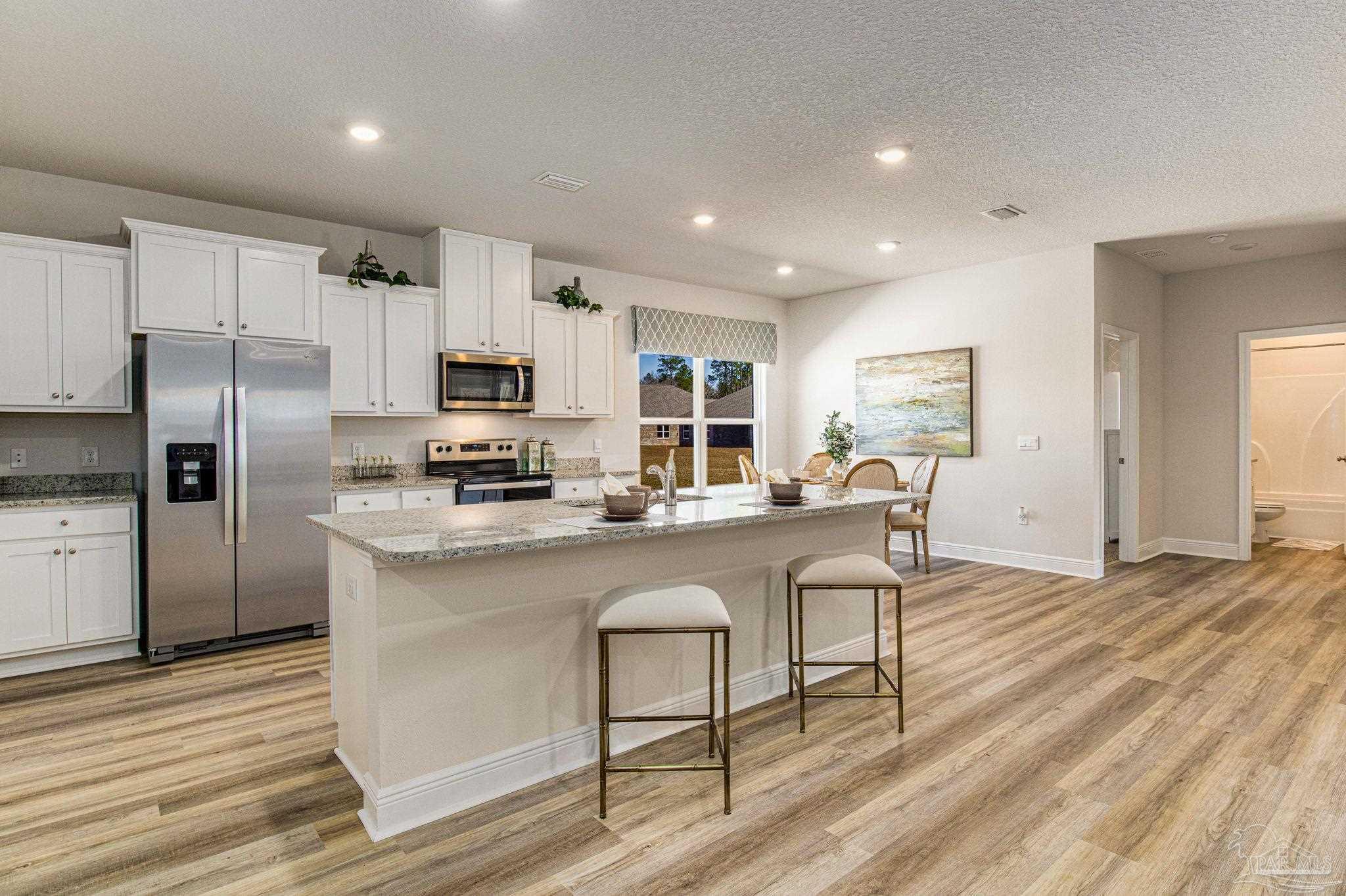 3821 Eagle Tail Drive Jay, FL 32565 - Photo 15 of 27 a kitchen with stainless steel appliances granite countertop a refrigerator a stove top oven a sink dishwasher a dining table and chairs with wooden floor