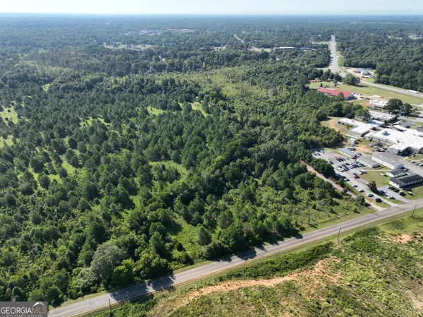 an aerial view of residential house with outdoor space and trees all around