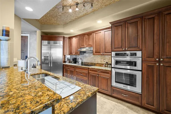 a kitchen with stainless steel appliances granite countertop a stove refrigerator and cabinets