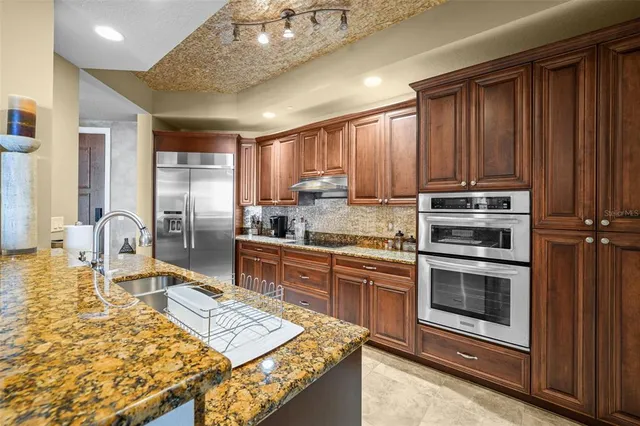 a kitchen with stainless steel appliances granite countertop a stove refrigerator and cabinets