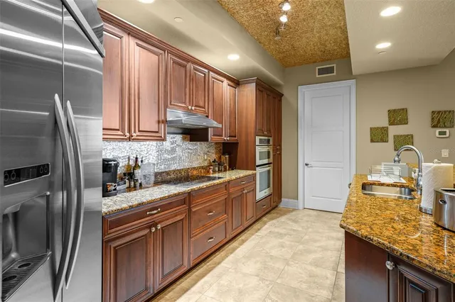 a kitchen with stainless steel appliances granite countertop a sink stove and refrigerator