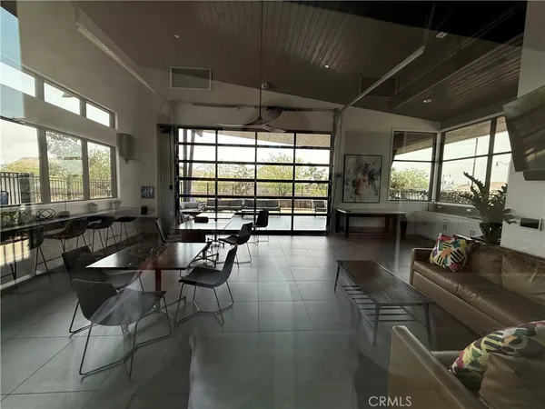 a living room with furniture a flat screen tv and floor to ceiling window
