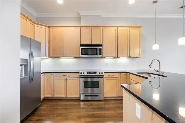 a kitchen with stainless steel appliances granite countertop a stove a sink and a microwave