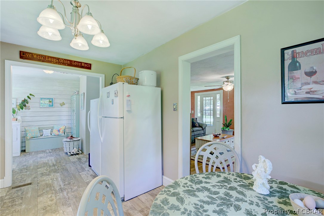 2442 Old Ferry Road Hudgins, VA 23076 - Photo 6 of 33 Kitchen with white fridge, wood-type flooring, ceiling fan with notable chandelier, and pendant lighting