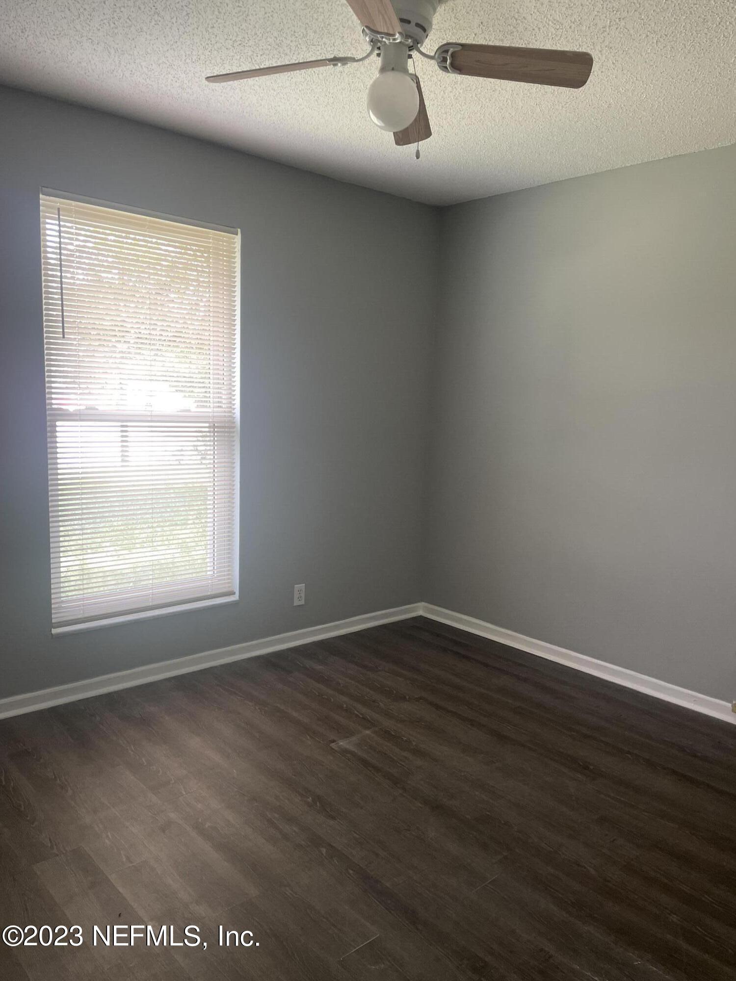 7952 Gulf Road South Jacksonville, FL 32244 - Photo 6 of 14 an empty room with wooden floor fan and windows