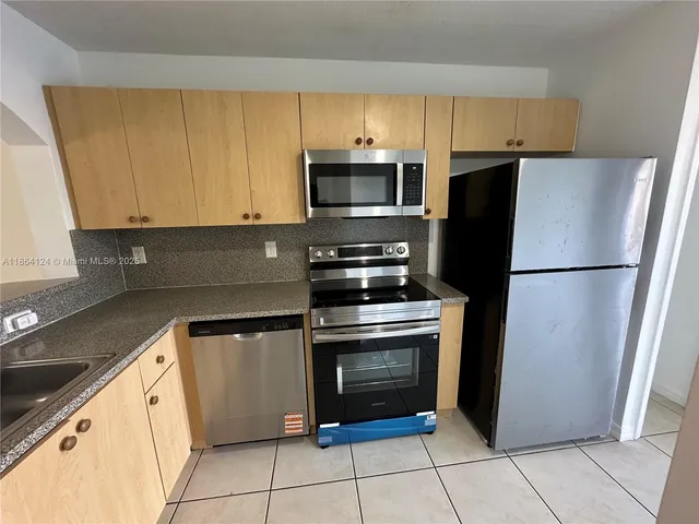 a kitchen with cabinets stainless steel appliances and a counter space