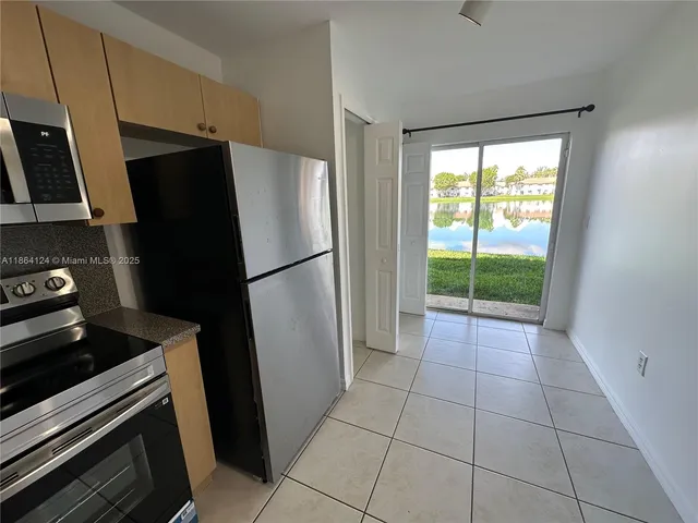 a kitchen with a refrigerator a stove top oven a counter space and a window