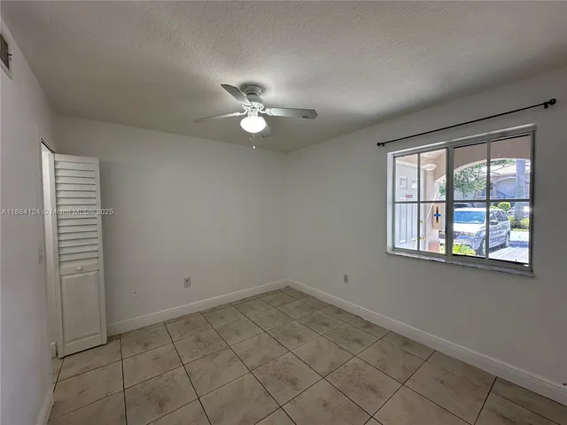 an empty room with a window and ceiling fan