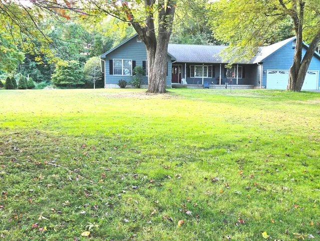 a view of a house with a yard and large tree